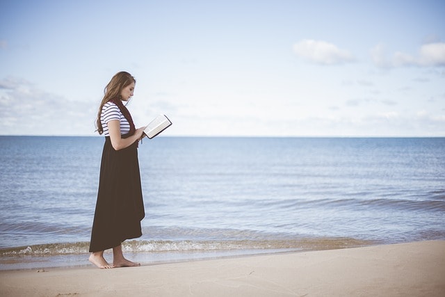 海沿いで本を読んでいる女性の様子